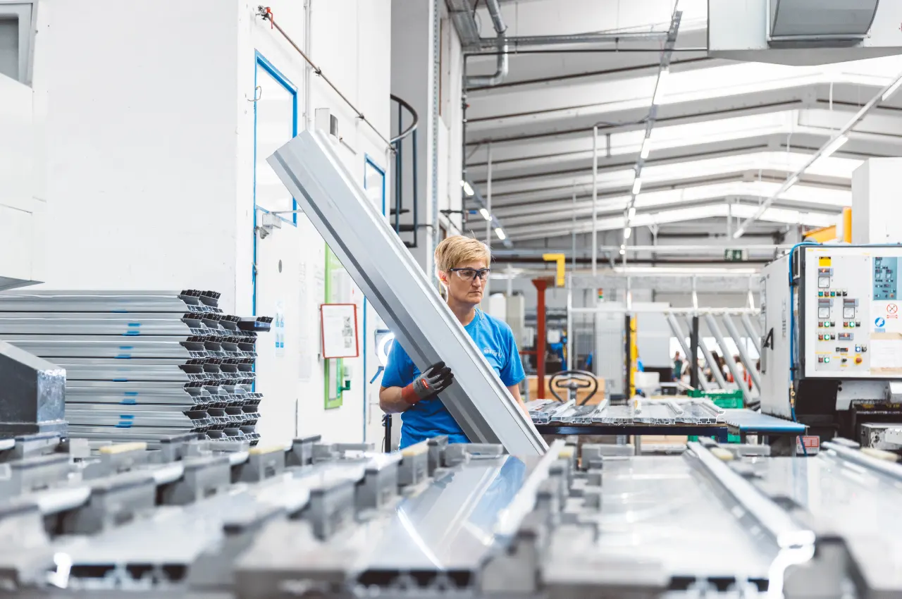 Operator loading an aluminium profile into a machine